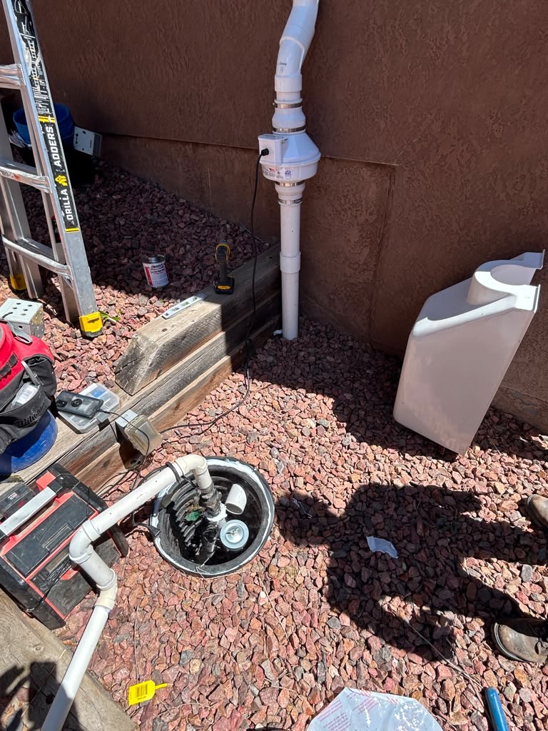 Sump pit and pump being installed with the radon vent and fan routed up the exterior wall