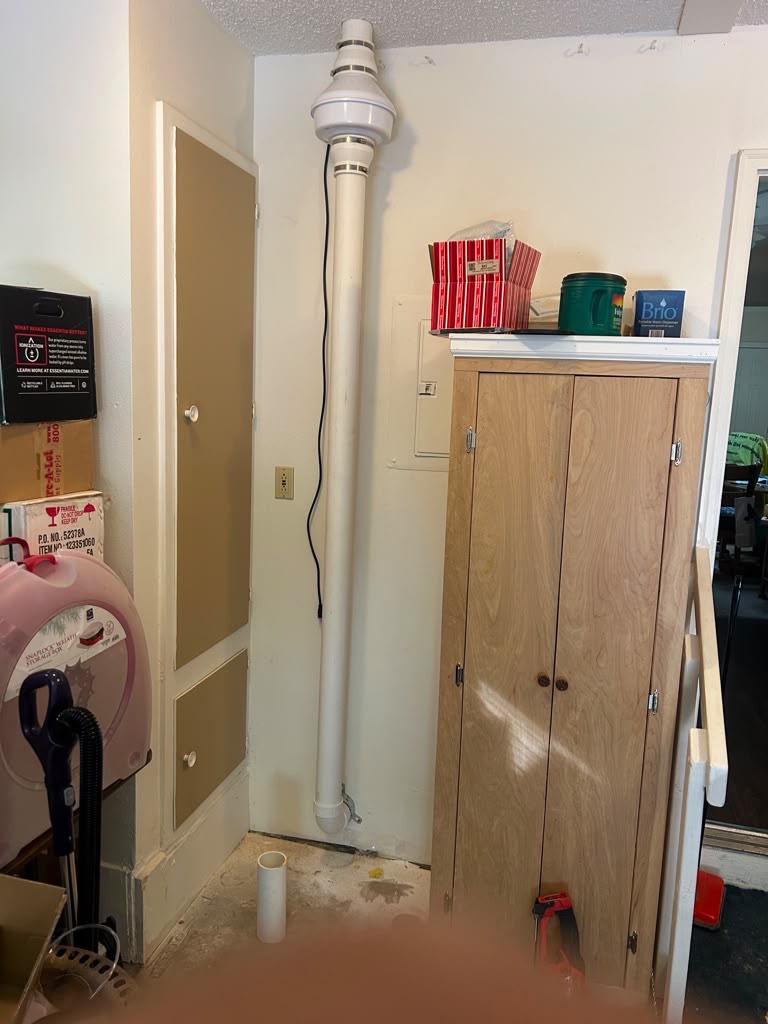 Interior radon pipe and fan installed in the corner of a utility room